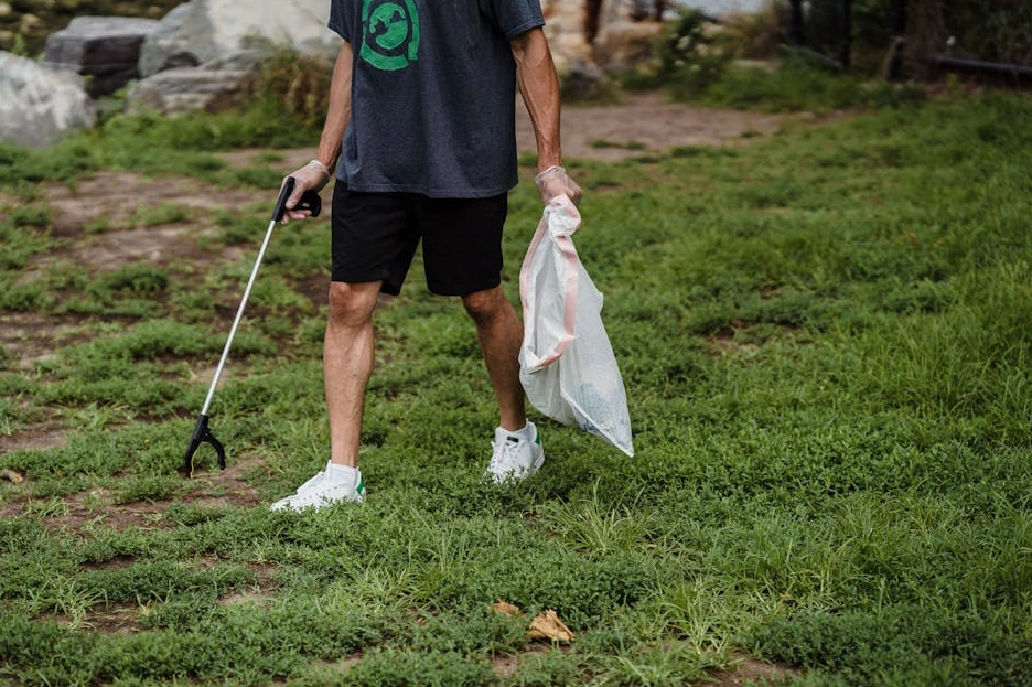 Grupa wolontariuszy sprzątająca park miejski w słoneczny dzień.
